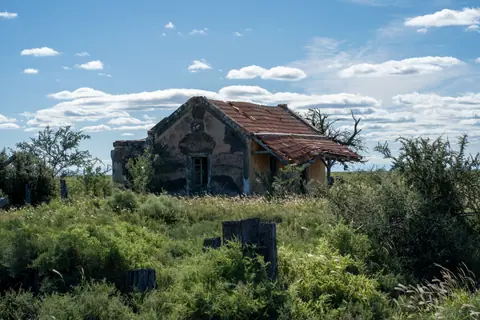 Explore an old, rural abandoned house amidst lush greenery under a clear sky in Córdoba, Argentina.