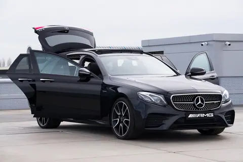 Sleek black luxury car with open doors showcased on a rooftop parking area.