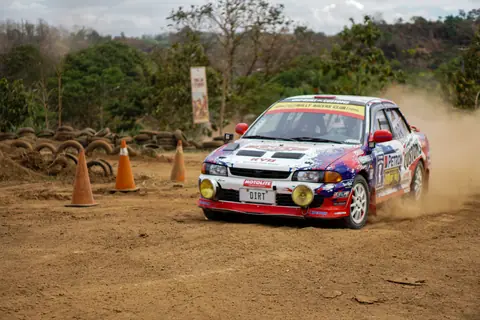 A thrilling rally car speeds around a dirt track, kicking up dust in Baras, Philippines.