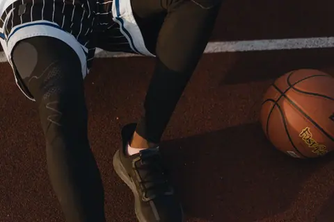 Dynamic close-up of a basketball player resting on an outdoor court with ball.
