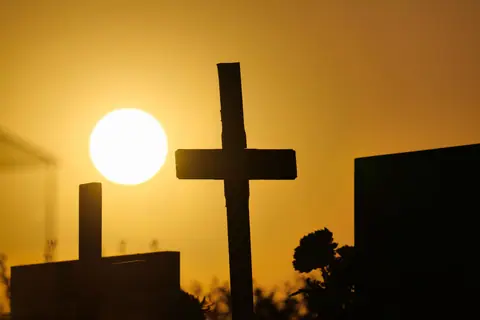 Wooden crosses in a cemetery silhouetted against a vibrant sunset in Garešnica, Croatia.