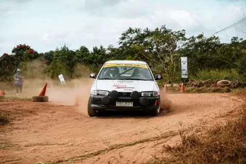A rally car speeds through a dusty off-road track, capturing the thrill of racing.