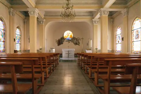 Peaceful church interior featuring elegant stained glass windows and wooden pews.