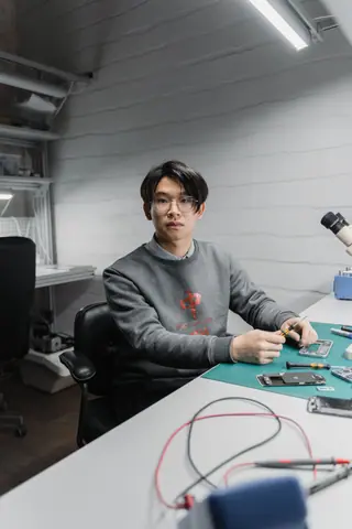 Focused young man working on electronic devices in a modern workspace.