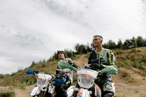 Two motorcyclists on dirt bikes enjoying a sunny off-road adventure.