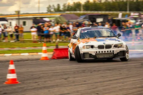 Race car drifting on circuit with spectators in the background.