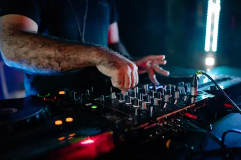 DJ mixing music at a vibrant nightlife event. Captured with colorful lights.