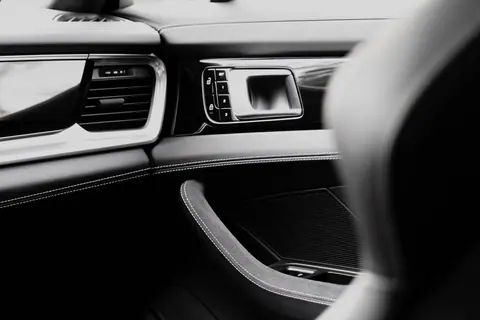 Close-up of a luxury car interior with a focus on the sleek dashboard and leather stitching.