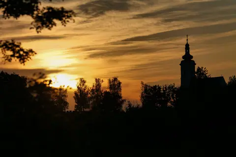 Silhouette of a church and trees in Garešnica, Croatia, at sunset.