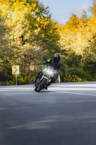 A biker skillfully navigates a sharp curve on a forest road in autumn.