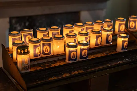 Warm glow of prayer candles inside a chapel in Italy, creating a serene spiritual ambiance.