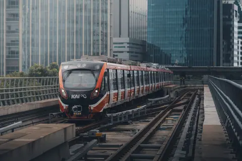 A modern train riding through urban tracks in Jakarta, showcasing the city's dynamic architecture.