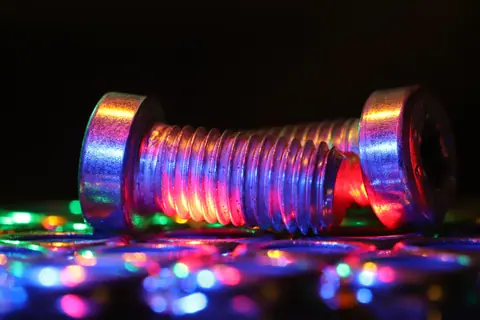 A detailed image of metal bolts illuminated by colorful lights, creating a bright, festive ambiance.