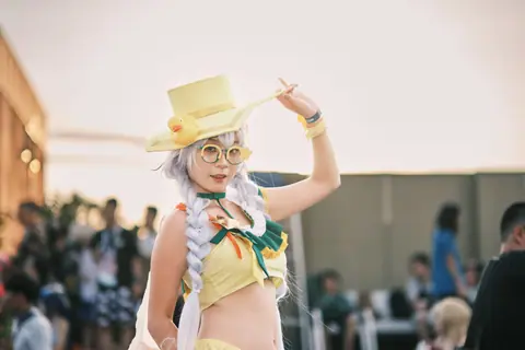 Cosplayer in vivid costume with yellow hat and accessories in an outdoor setting.