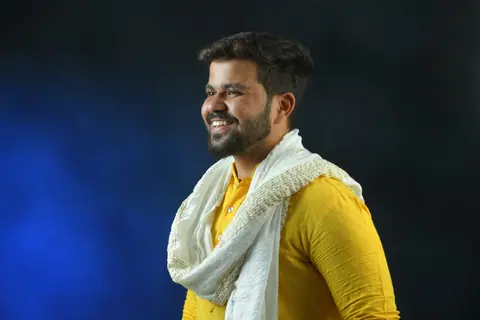 Portrait of a smiling man in a vibrant yellow kurta and white scarf, showcasing traditional Indian style.