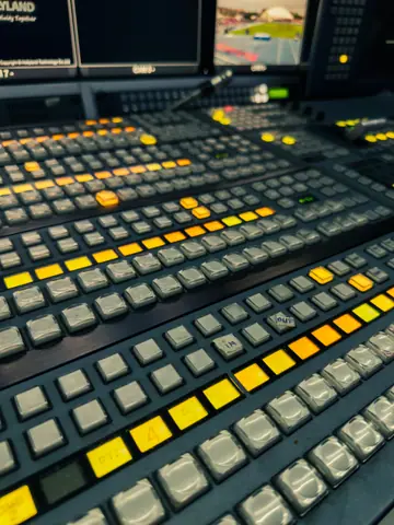 Detailed view of a studio broadcast control panel with illuminated buttons, showcasing advanced technology in media production.