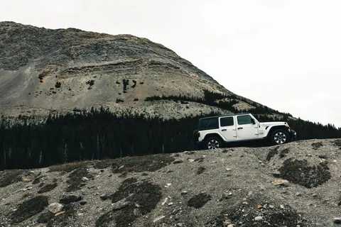 A 4x4 vehicle navigates rugged terrain in Banff National Park, Canada.