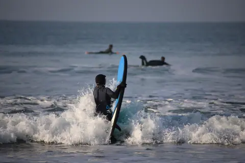 Surfers enjoy water sport in the ocean waves of Pays de la Loire, France.