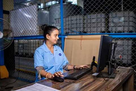 A female factory worker using a computer in an industrial environment.