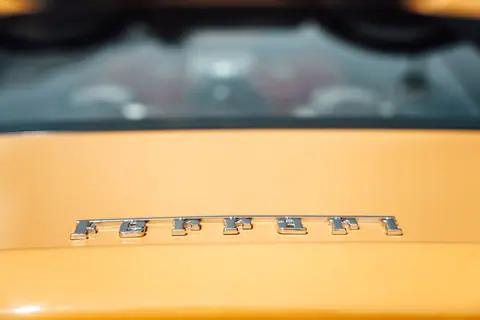 Detailed view of a yellow Ferrari emblem on a luxury sports car.