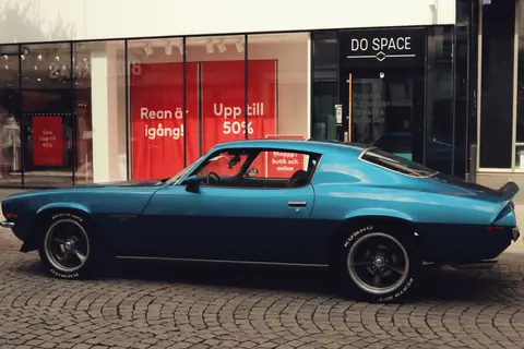 Classic blue Chevrolet Camaro parked on urban street in Jönköping, Sweden. Retro car adds vintage charm to urban scene.