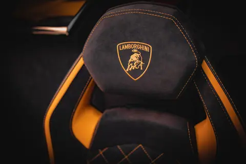 Close-up of a luxury Lamborghini seat interior design, featuring black and yellow leather stitching.