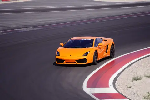 Dynamic shot of an orange sports car racing on a track in Las Vegas, showcasing speed and precision.