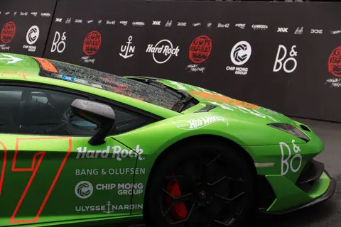 Green sports car featuring prominent brand logos on a racing event backdrop.