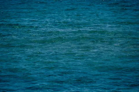 From above of surface of wavy blue sea on sunny day as background
