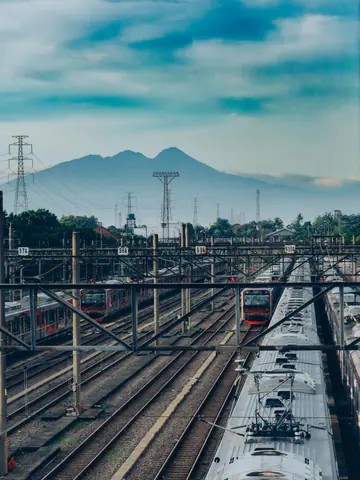 Morning view of trains against Mount Salak from Depok, Indonesia illustrating daily commute.