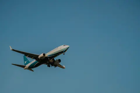 Low angle shot of a commercial airplane flying against a clear blue sky.