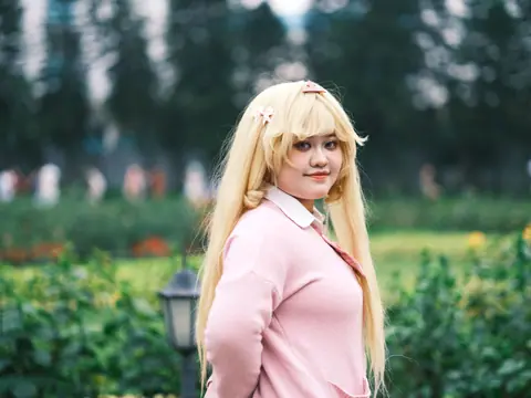 Cosplay enthusiast posing outdoors in a vibrant, lush Vietnamese garden setting.