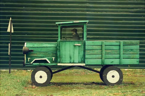 Charming wooden truck sculpture in rustic green hues evokes vintage rural life ambiance.