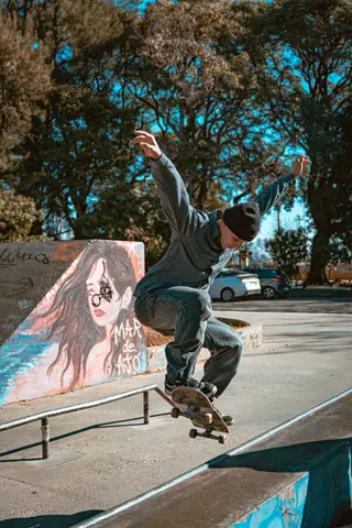 Dynamic image of a skateboarder executing a trick in a Buenos Aires plaza with vibrant mural art behind.