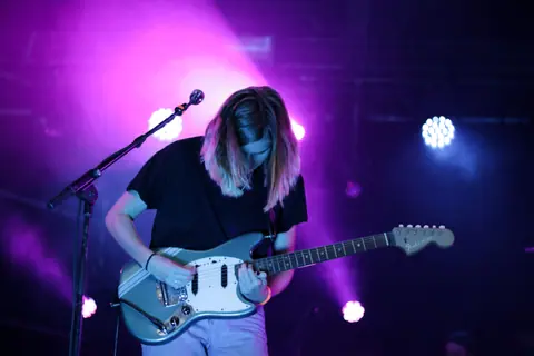 A captivating guitarist performs in vibrant lighting at a live concert in Breda, Netherlands.