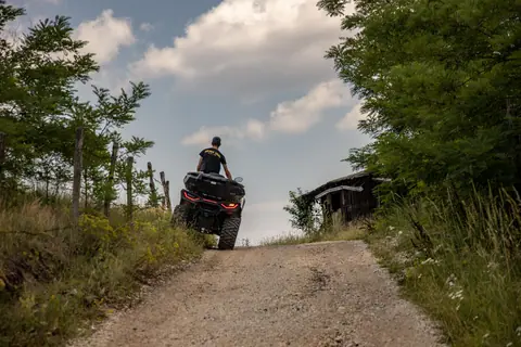 A person riding an ATV up a gravel road surrounded by lush greenery in Zlatibor, Serbia.