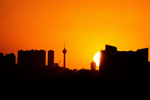 Silhouette of city skyline against a vibrant sunset sky.