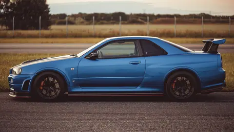 Side view of a blue Nissan Skyline GTR parked on a country road in Roskilde, Denmark.