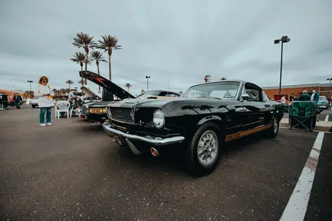 A classic car show featuring vintage Mustang models with people enjoying the outdoor event.