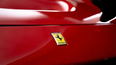Close-up view of a shiny red sports car with emblem for luxury branding.