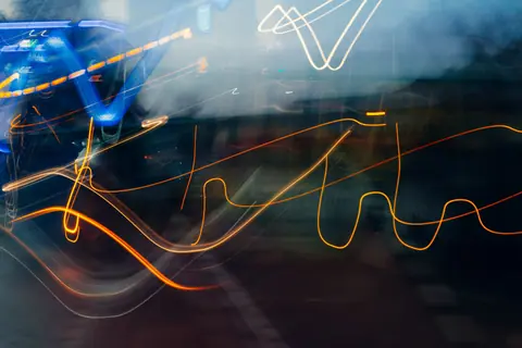 Abstract light trails create a dynamic urban night scene with vibrant motion and color.