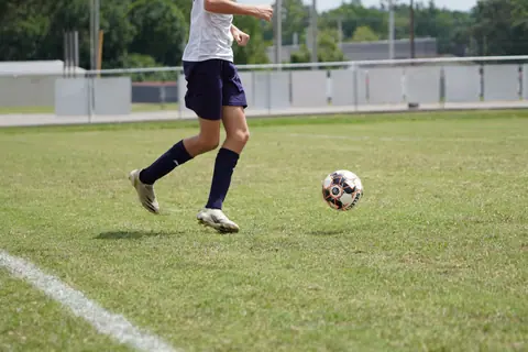 A young soccer player in action on an outdoor field during the day.