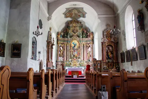 A beautiful view of a historical church interior showcasing intricate altarpiece and wooden pews.