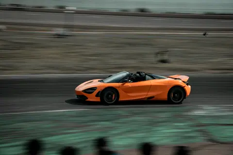 Orange supercar speeding on a race track in Colorado, showcasing automotive excellence.