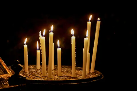 A peaceful scene of votive candles burning in a dimly lit church, symbolizing hope.