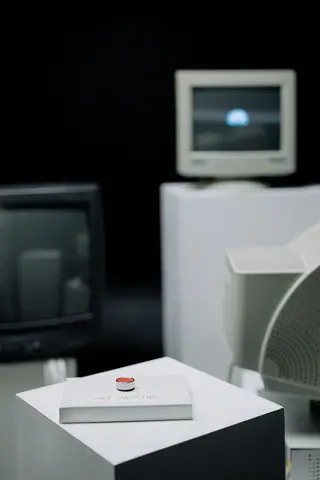 Vintage computer setup featuring a prominent red alert button emphasizing urgency.