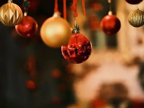 Close-up of shiny red and gold Christmas ornaments hanging indoors, capturing festive holiday spirit.
