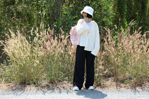 Woman with backpack standing roadside in rural Vietnam, embracing nature.
