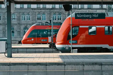Red trains at Nürnberg Hauptbahnhof station on a sunny day, showcasing public transportation.