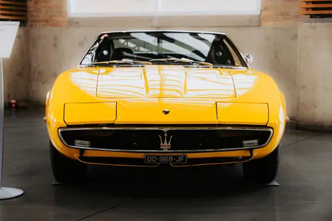 A classic yellow sports car showcased indoors, highlighting its sleek design and vintage appeal.